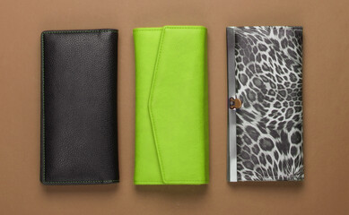 Three stylish wallets on brown background. Fashion minimalism. Top view