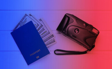 Passport with dollar bills and camera. Neon light.  Flat lay travel composition. Top view