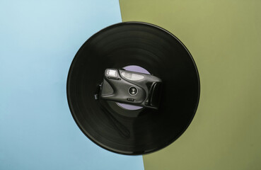 Vinyl record with a retro camera on colored pastel background. Top view