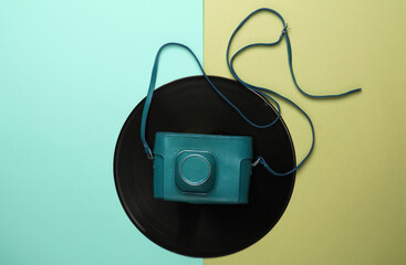 Vinyl record with a retro camera on colored background. Top view
