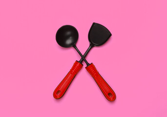 Toy kitchen tools on pink background. Kitchen spatula, ladle. Top view