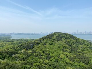 Wuhan East Lake scenic spot.  Cable car on the green Moshan Hill. East Lake and Wuhan skyline