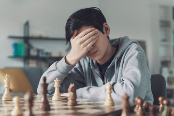 Boy playing chess and losing the game - obrazy, fototapety, plakaty