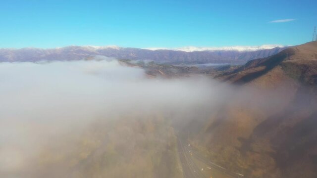 Aerial Over Clouds And Fog Reveals The Ojai Valley And Snow Covered Topatopa Mountains In Winter.