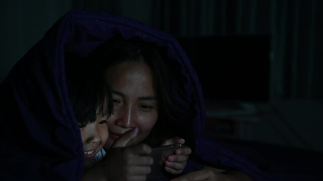 Asian Mom and daughter play smartphone in the bed at night,Thailand people,Addict social media,Play internet all night