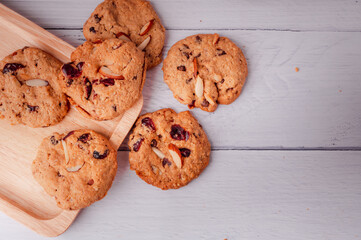 Piles of delicious chocolate chip cookies on a white plate with a milk bottle. Pastry utensils with white linen napkins on a wooden table. Delicious on a white plate with a bottle of milk.