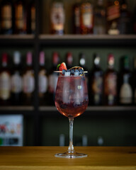 Refreshing red summer cocktail with ice based on gin, strawberry's syrup and cranberry's syrup  
