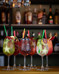 Six colorful gin tonic cocktails in cocktail glasses on bar counter