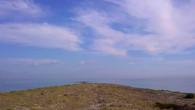 Low fast aerial pass along low headland towards ocean horizon