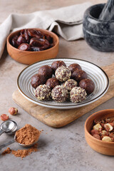 A plate with homemade raw chocolate energy balls, dates and hazelnut. Healthy vegan and vegetarian food.