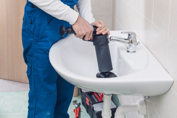 Professional plumber unclogging a sink