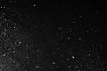 Drops of water and ice on the glass on a black background. Abstract texture dark bokeh background with copy space. Defocusing. High quality photo
