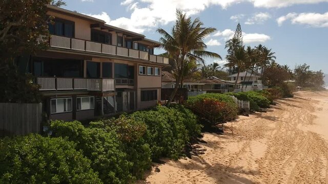 Shots panning the real estate and tree line along Oahu's Northshore during a surfing event.
