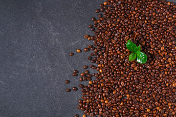 Roasted brown coffee beans on a gray background. Template for advertising coffee. Top view.