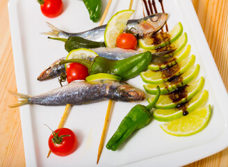 Grilled sardines with fresh vegetables served with lime and balsamic pasta on plate