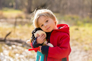 Little toddler blond child, boy, playing with handknitted doll