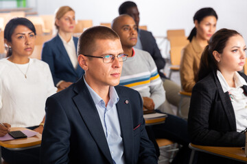 Portrait of focused male attentively listening to lecture with colleagues at conference