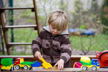 Toddler child, boy, playing in sandpit at backyard