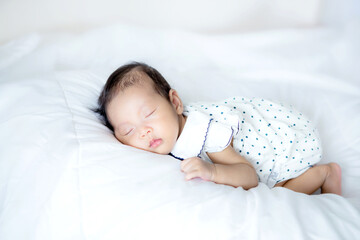 Close up adorable asian 3 months years old baby girl sleeping on a white bed , newborn peace sleeping concept
