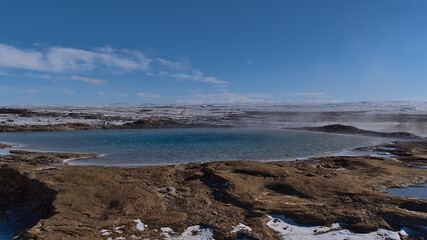 Steaming hot water pool of The Great Geysir, name giver for all geysers worldwide, in Geysir in geothermal area Haukadalur, part of Golden Circle, Iceland in winter season on sunny day.