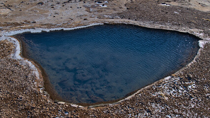 Hot spring with pool of clear, blue shimmering thermal water in Geysir in geothermal area...