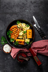 Grilled chicken breast with corn and zucchini on a grilled pan top view. Summer dish with grilled chicken and vegetables. Vertical photo with copy space for text