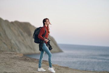 woman in the mountains outdoors near the sea on the beach with a backpack on her back