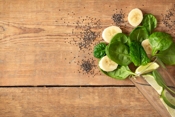 Healthy food concept. Ingredients for cooking detox smoothie. Glass with spinach, banana, lime and chia seeds on wooden table top view, copy space