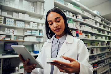 Female african american pharmacist working in chemist checking medicine details in digital tablet