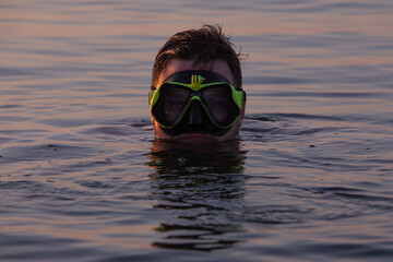 man with snorkeling mask in water on sunset
