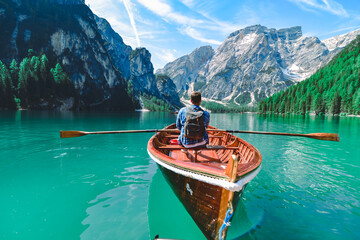 man rowing in big wooden boat at mountain lake