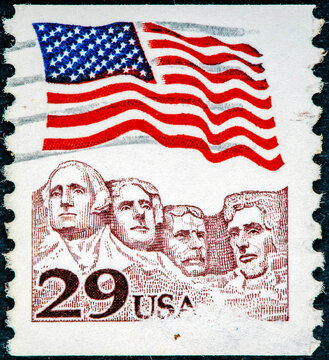 stamp printed in the USA shows American flag waving above Mt. Rushmore