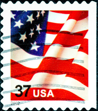 stamp printed in the United States, features waving US flag, first-class