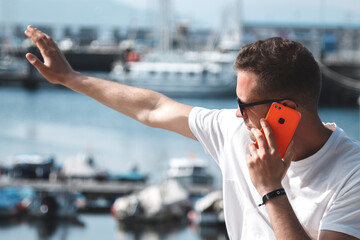 tourist man with mobile phone waving, in front of the seaport, traveling man