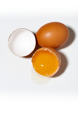 broken and whole chicken egg on white background, vertical top view