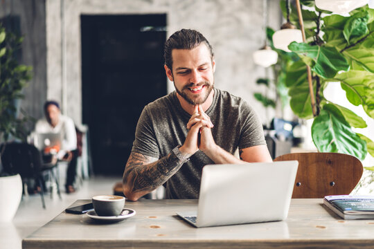 Handsome bearded hipster man use and looking at laptop computer with coffee at table in cafe.Communication and technology concept