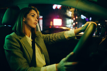 Young woman driving car alone at night.