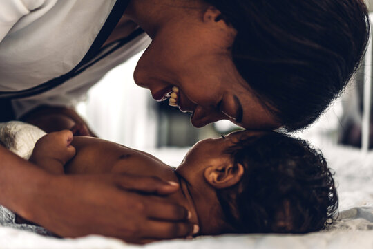 Portrait of enjoy happy love family african american mother playing with adorable little african american baby.Mom touching with cute son moments good time in a white bedroom.Love of black family