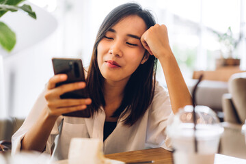 Portrait of smiling happy beautiful asian woman relaxing using digital technology smartphone.Young asian girl looking at screen typing message and playing game online or social media at cafe