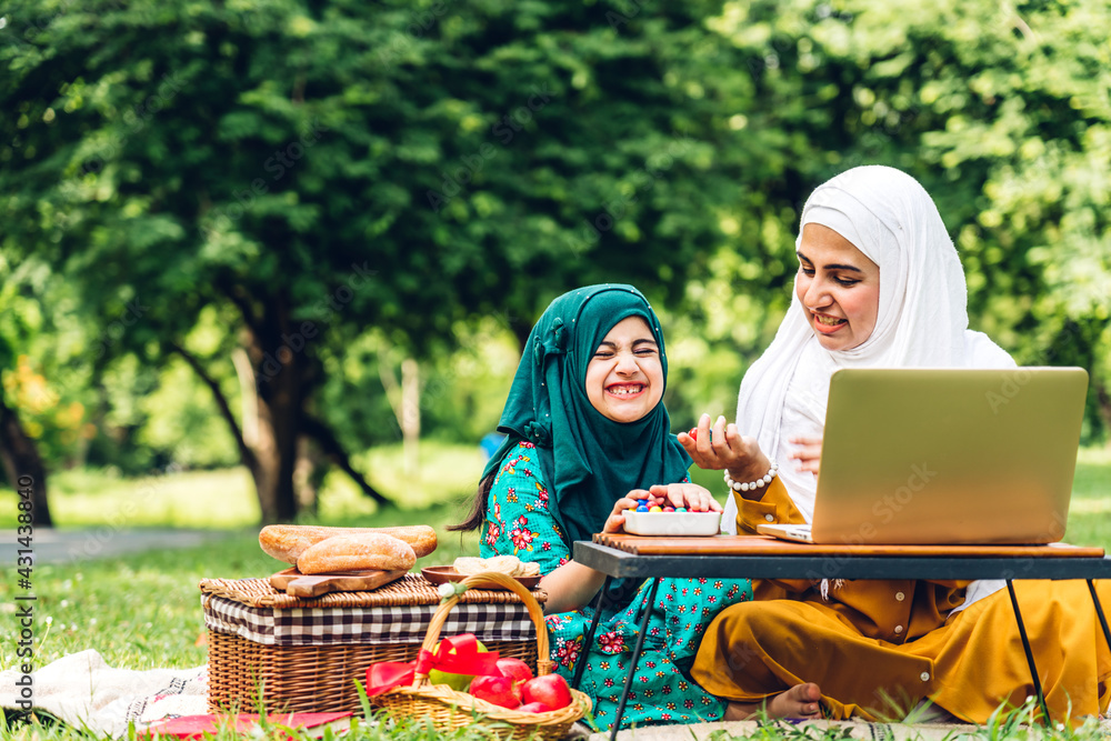 Wall mural Portrait of happy religious enjoy happy love asian family arabic muslim mother and little muslim girls child with hijab dress smiling and having fun moments good time in summer park