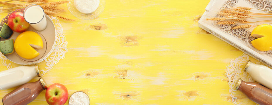 Top view photo of dairy products over yellow wooden background. Symbols of jewish holiday - Shavuot