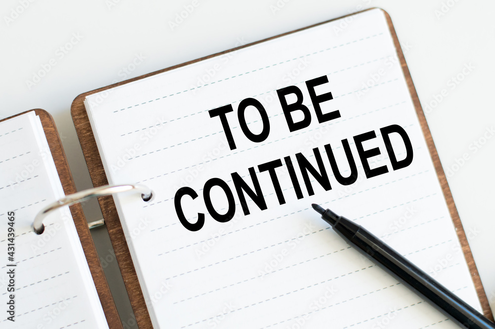Poster notebook with with text to be continued next to black marker on table