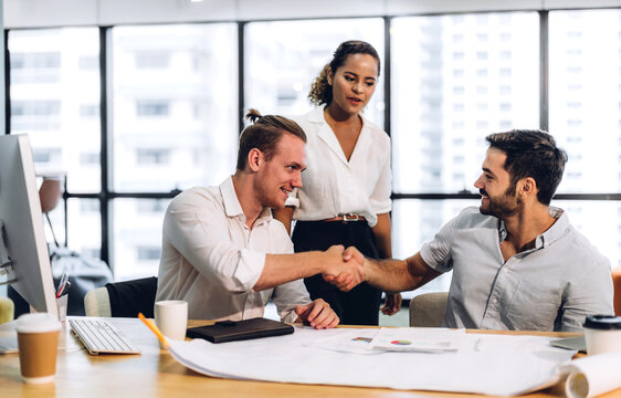 Image two business partners successful handshake together in front of teamwork casual business winning success agreement in modern office.Partnership approval and teamwork