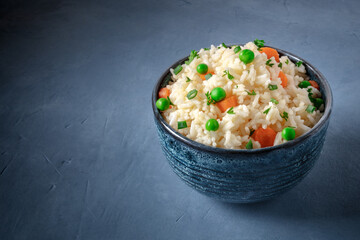 Rice with green peas, carrots, and scallions, on a blue background