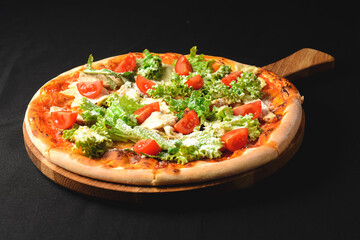 Caesar pizza isolated on lack background. Italian pizza with caesar salad filling.
