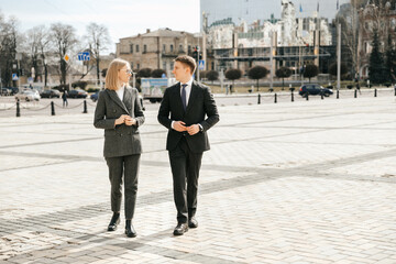 A couple of business people are walking around the city in office suits outside the office. Successful and attractive office workers