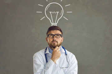 Studio portrait of young physician in glasses and white doctor's lab coat with stethoscope...