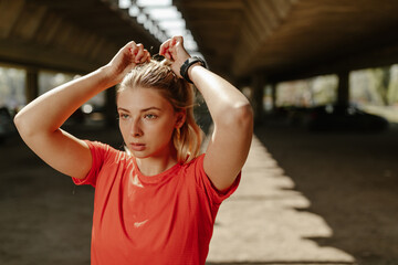 Athletic beautiful woman tying her hair. Sporty woman getting ready for workout.