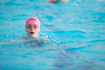 Child athlete swims in the pool. Swimming section.