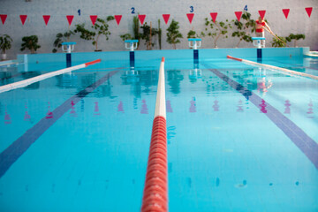 An empty sports pool with a red dividing path. Blue water in the swimming pool.